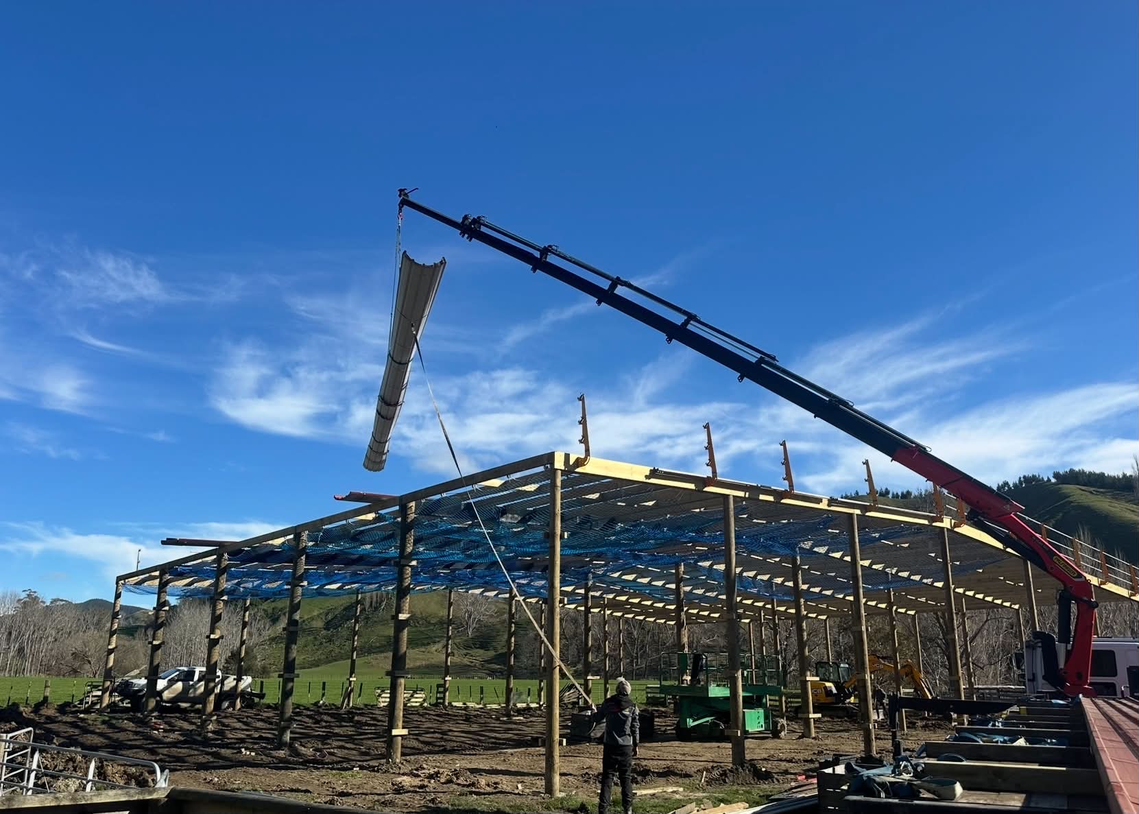 Crane lifting a roof sheet onto a shed frame